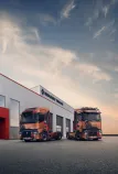 Two Renault Trucks T High tractor units are parked in front of a Renault Trucks dealership at dusk.